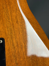 Close-up of a wooden guitar with a white pickguard and dark background