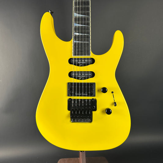 Yellow electric guitar on a stand against a dark background