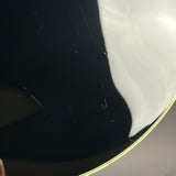 Close-up of a glossy black curved surface with a thin gold edge, showing some visible scratches and a bright white reflection.