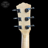 Close-up of the headstock of a guitar, showing six silver tuning pegs with black circular centers and a light natural wood grain finish, set against a solid black background. A Tone Shop watermark is visible in the top-left corner.