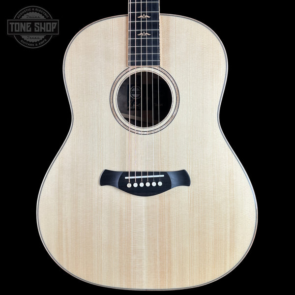 An acoustic guitar with a natural wood finish and black hardware, shown against a solid black background with a Tone Shop logo in the top-left corner.