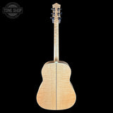 Back view of a wooden acoustic guitar on a black background with 'Tone Shop' logo.