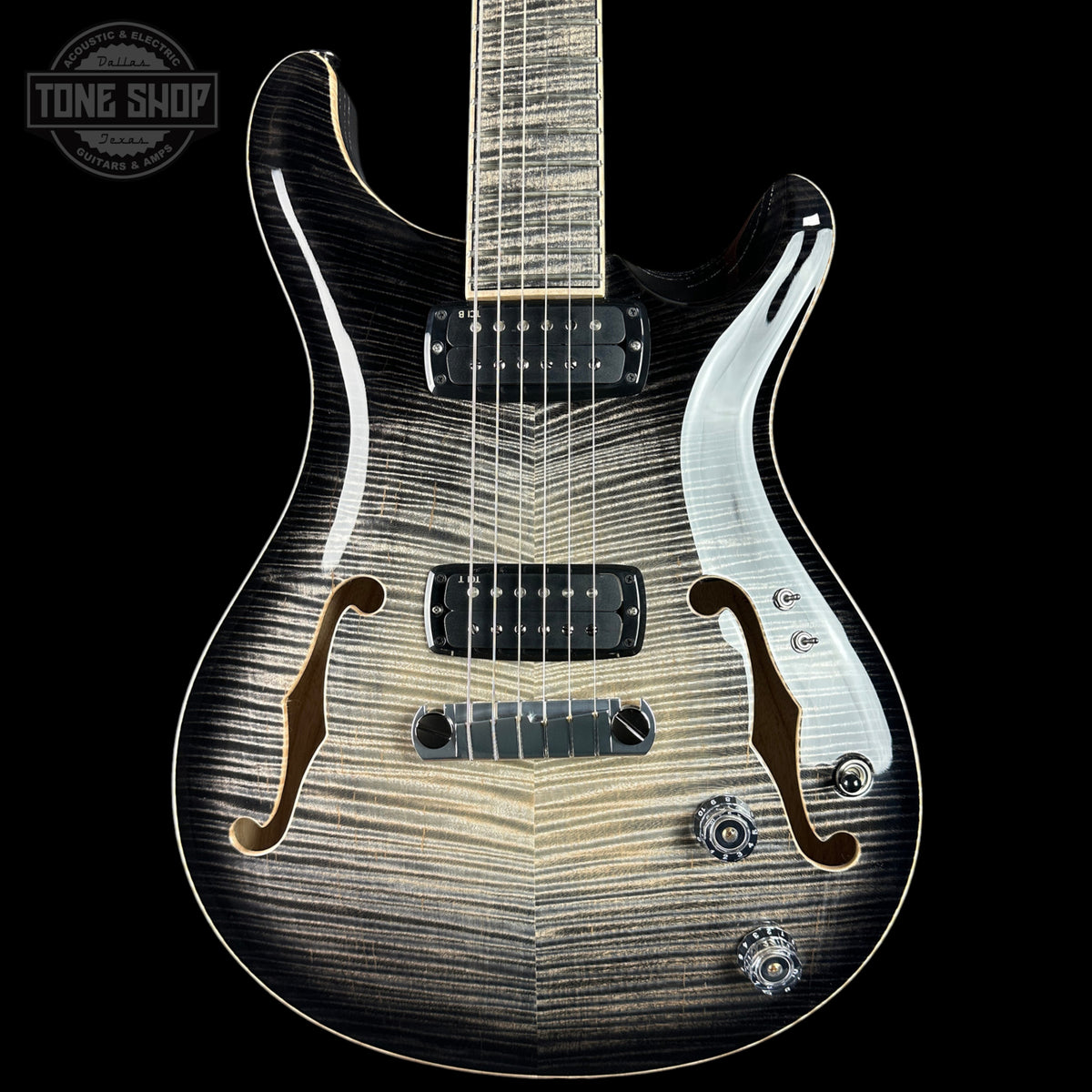 A close-up studio shot of an electric guitar body against a black background, showing a black-to-brown flame finish with a white pickguard and chrome hardware. A Tone Shop watermark is visible in the top-left corner.
