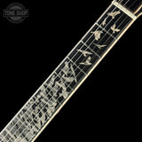 Close-up of a guitar fretboard featuring inlaid bird motifs on a black background, with a Tone Shop watermark in the top-left corner.