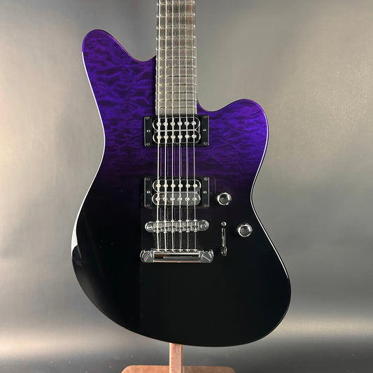 Purple and black electric guitar on a stand with a neutral background