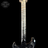 Close-up of the neck and lower body of an electric guitar against a black background, showing a glossy black body with white swirling flame patterns and a flamed maple neck.