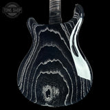 A close-up of a guitar body featuring a glossy black finish with dramatic white and gray agate-like wavy lines, shown against a solid black background. A Tone Shop watermark is visible in the top-left corner.