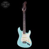 A light blue electric guitar with a white pickguard and gold hardware, shown against a solid black background. A Tone Shop watermark is visible in the top-left corner.