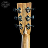 Close-up of a wooden guitar headstock with six black and gold tuning pegs on a solid black background. A Tone Shop watermark is visible in the top-left corner.