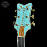 Gretsch guitar headstock with turquoise background and gold accents on a black background