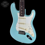 A light blue electric guitar with a white pickguard, cream-colored controls, and a dark fretboard, shown against a solid black background. A Tone Shop logo is visible in the top-left corner.