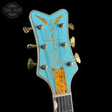 Gretsch guitar headstock with turquoise and gold design on a black background