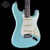A light blue electric guitar with a white pickguard and cream-colored controls, shown against a solid black background with a Tone Shop watermark in the top left corner.