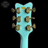Turquoise guitar headstock with gold tuning pegs on a black background, featuring the Tone Shop logo.