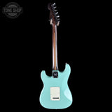 A mint green electric guitar shown from the back against a solid black background, featuring a white pickguard and a brown wood neck.