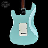 The back of a Fender electric guitar in a light mint green finish, featuring a silver plate, control plate, and dark wood neck against a black background.