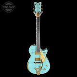 Light blue electric guitar with gold accents on a black background, featuring 'Tone Shop' logo.