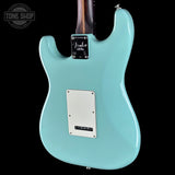 The back of a Fender electric guitar in a glossy light blue finish, featuring a silver plate and a dark wood neck, shown against a solid black background.
