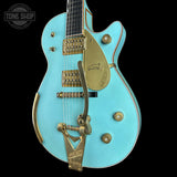 Turquoise electric guitar with gold hardware on a black background, featuring 'Tone Shop' logo.