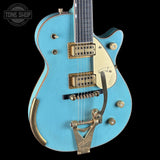 Blue electric guitar with gold hardware on a black background, featuring 'Tone Shop' branding.