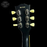 Close-up of the headstock of a black electric guitar against a black background, showing six silver tuning pegs with cream-colored knobs and the model number 961843 printed on the headstock. A Tone Shop watermark is visible in the top left corner.