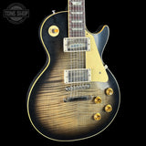 A Gibson Les Paul Custom electric guitar with a natural flame maple top, black body, cream pickguard, and gold hardware, shown against a black background with a Tone Shop watermark in the top left corner.