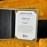 An open Gibson Custom Certificate of Authenticity booklet for a Murphy Lab Light Aging instrument, displayed on a textured golden-yellow surface.