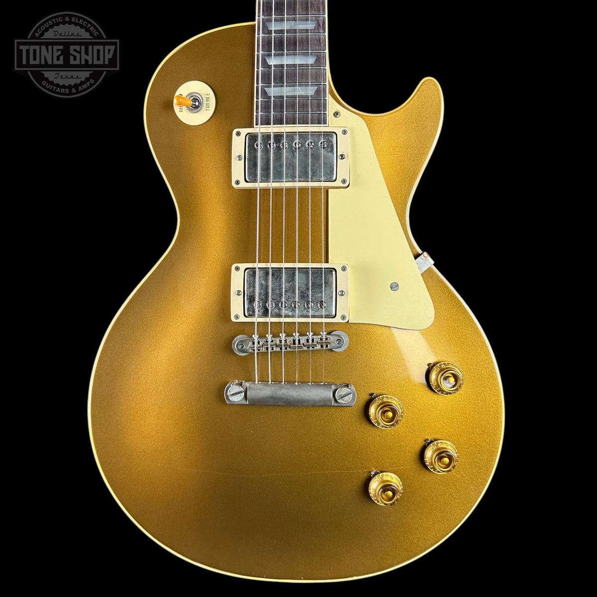 Gold electric guitar with a 'Tone Shop' logo in the corner