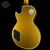A gold electric guitar body shown from the back against a black background, with a circular 'Tone Shop' watermark in the upper left corner.