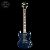 A blue electric guitar with a dark blue finish, set against a solid black background. The brand 'Gibson' is visible on the headstock, and a 'Tone Shop' watermark is in the top-left corner.