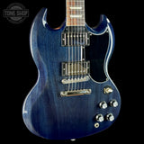 A blue Gibson SG electric guitar with a dark blue wood grain finish, chrome hardware, and a black pickguard, shown against a solid black background with a Tone Shop watermark in the top left corner.