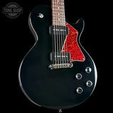 A black electric guitar with a red glitter-style pickguard and chrome hardware, shown against a black background with a Tone Shop watermark in the top left corner.