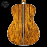 Back view of a wooden acoustic guitar with 'Tone Shop' logo.