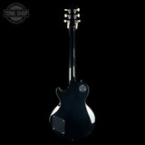 A black electric guitar shown from the back against a solid black background, with a Tone Shop watermark in the top-left corner.