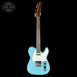 Blue electric guitar with a white pickguard on a black background, featuring the Tone Shop logo.