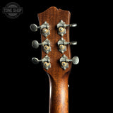Close-up of the headstock of a wooden acoustic guitar against a solid black background, showing six silver tuning pegs with gold-toned centers. A 'TONE SHOP' watermark is visible in the top left corner.