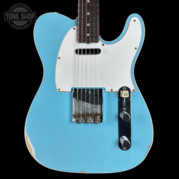 Blue electric guitar with a white pickguard on a black background, featuring 'Tone Shop' branding.