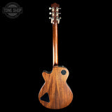 A back view of a wooden six-string electric guitar against a solid black background, featuring a glossy brown wood finish and a circular Tone Shop logo in the top-left corner.