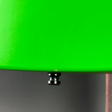 Close-up of a bright green circular product surface with a small black metal connector or screw detail near the bottom edge, set against a dark gray background.