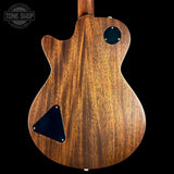 The back of a double-cutaway electric guitar with a rich brown wood grain finish, featuring black pickguard and circular control knobs, shown against a solid black background.