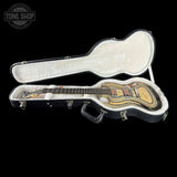 An electric guitar with a distinctive striped natural wood body, shown inside an open black hard case with white padding. The brand 'Tone Shop' is visible as a watermark in the top-left corner.