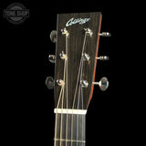 Close-up of the headstock of a Collings acoustic guitar against a black background, showing the brand name in white script and six tuning pegs.