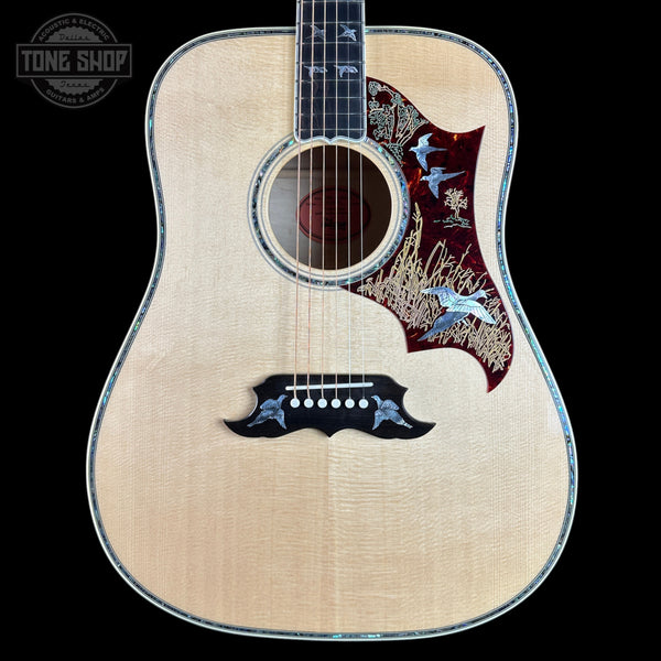 An acoustic-electric guitar with a natural wood body, featuring a decorative red and gold bird inlay on the upper bout, a black pickguard with matching bird motifs, and a dark fretboard, shown against a solid black background.