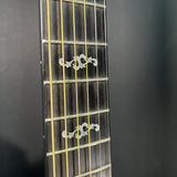 Close-up of a guitar fretboard with inlaid markers on a dark background