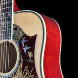 Close-up of an acoustic guitar body showing the red flamed wood outer shell, natural beige soundboard, and dark brown pickguard with inlaid bird and tree motifs.