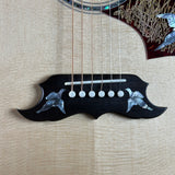 Close-up of a guitar's black bridge plate featuring intricate silver mother-of-pearl inlay of flying birds, with six white string beads and strings visible against a light beige wood-grain background.