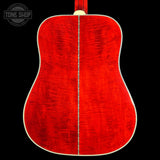 The back of an acoustic guitar with a vibrant red flamed maple top, a central sound hole, and a white binding, shown against a solid black background with a Tone Shop logo in the top-left corner.