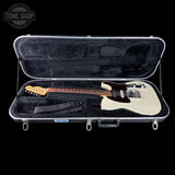 A Fender Telecaster electric guitar in an off-white finish with a dark brown pickguard and maple neck, displayed inside an open silver hard case with black velvet lining. The Fender logo is visible on the headstock and the case.