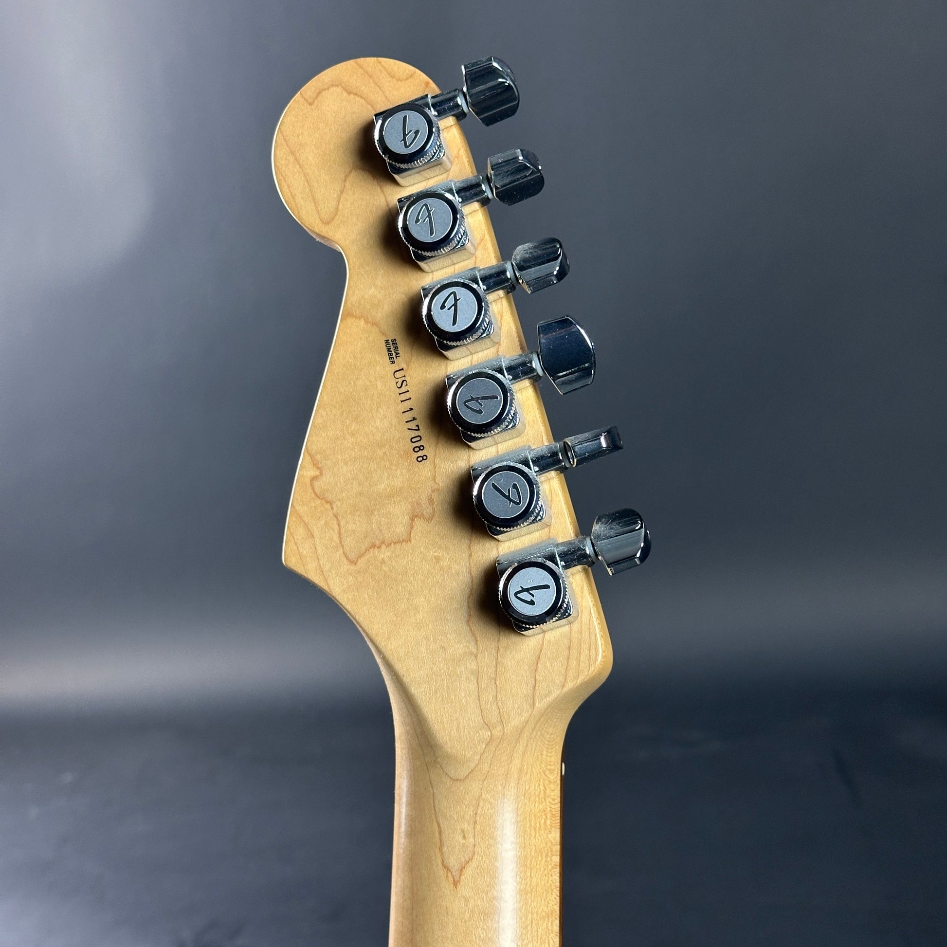 Guitar headstock with tuning pegs on a dark background