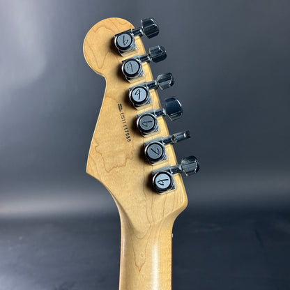 Guitar headstock with tuning pegs on a dark background